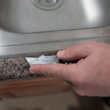Cutting caulk on a sink.