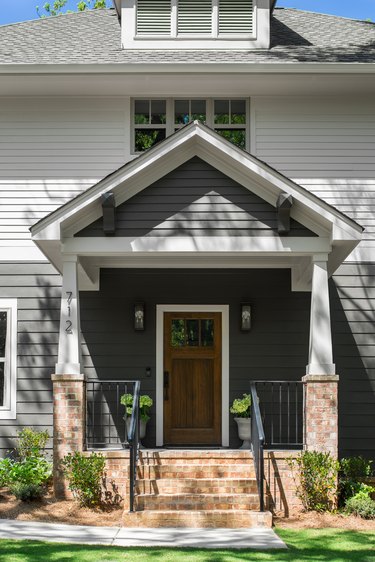 exterior door trim on gray and white house with wooden door and white trim