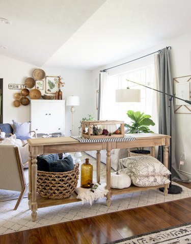 Rustic fall decor on foyer table with throw pillows and blanket in entryway