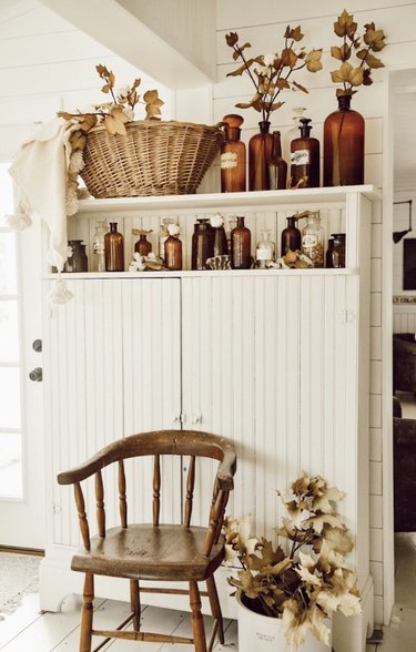 Rustic fall decor with vintage amber bottles and vintage white hutch