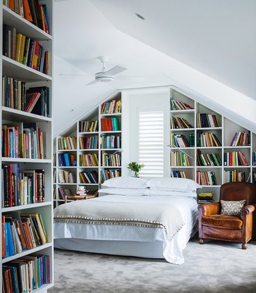 small attic library and bedroom with walls of bookshelves