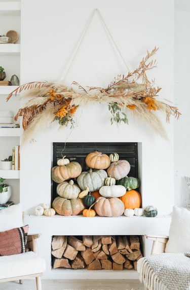 Rustic fall decor on fireplace mantle with natural wall hanging and pumpkins