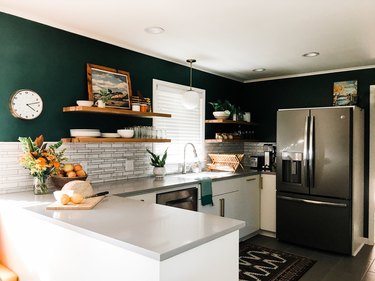 Dark green walls in an otherwise white and gray kitchen