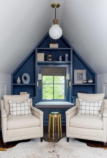 Small attic ideas with blue accent wall and two white fabric armchairs.