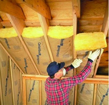 Worker installing fiberglass insulation.