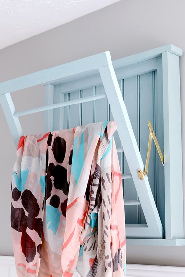 wall-mounted clothes drying rack in laundry room