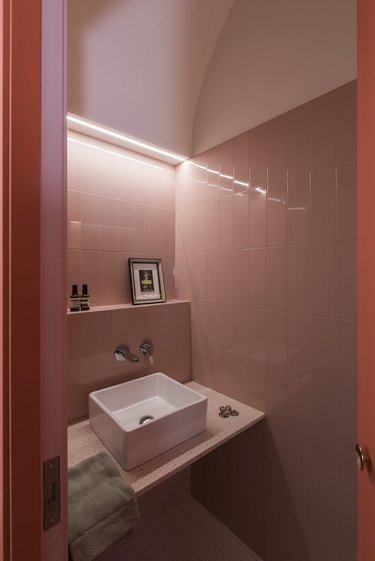 pink bathroom with dramatic lighting and floating vanity