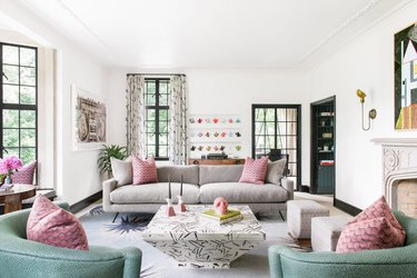 white maximalist living room with patterned pink pillows on the sofa