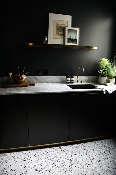 black kitchen with marble countertops and terrazzo floor