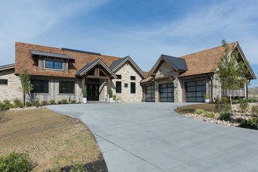 Stone for house exterior with brown shingle roof and wood siding