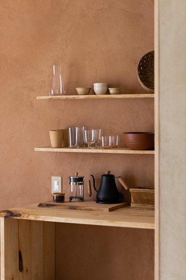 Pottery in shelves coordinates with hand-plastered walls.