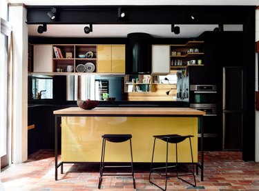 yellow kitchen cabinet idea with black cabinets in modern space with brick floors