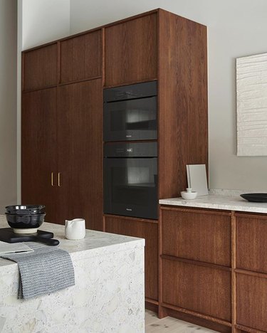 built-in wood kitchen cabinets with white countertops and black appliances