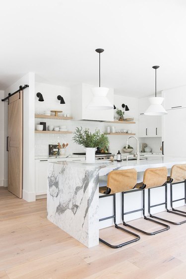 Modern kitchen island idea with marble waterfall countertop and pendant lighting