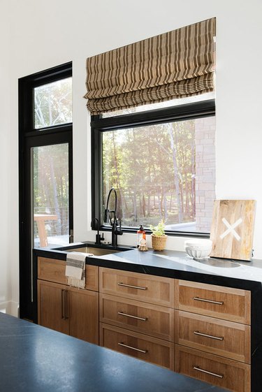 wood kitchen cabinets with black countertops and window trim