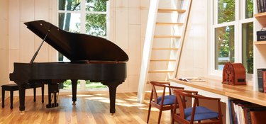 Black grand piano, light wood floors, attic stairs ideas, side chairs, wood desk and bookcase.
