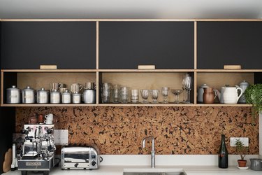 cork kitchen backsplash with black cabinets and white countertop