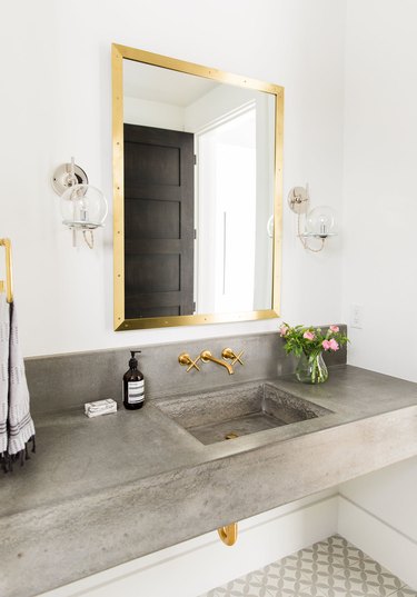 Modern concrete bathroom sink with brass accents and patterned floor tile