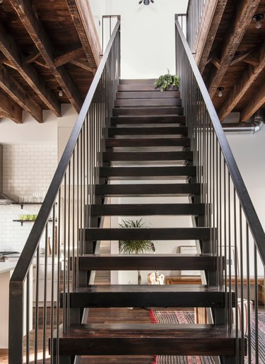 attic stairs ideas with black metal and wood industrial style stairs, exposed beam ceiling.