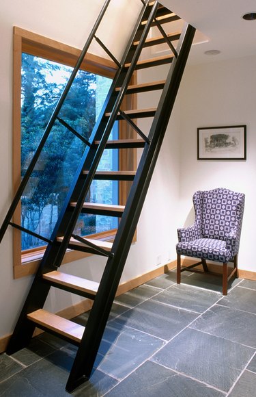 Black metal and wood attic stairs ideas, picture window, wing back chair, slate tile floor.