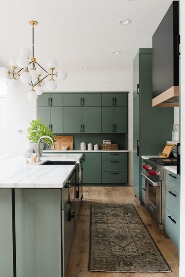 Kitchen organization ideas in space with modern chandelier and green cabinetry
