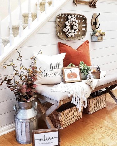 rustic fall decor in entryway with pillows and seasonal foliage