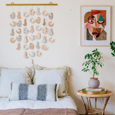 room showing bed, hanging wall art, side table with plant, and art print by Justina Blakeney