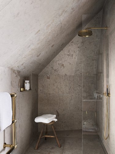 minimal rustic shower tile in in bathroom with half glass shower door and wood stool