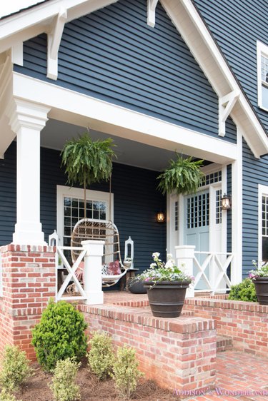 Blue farmhouse with brick porch.