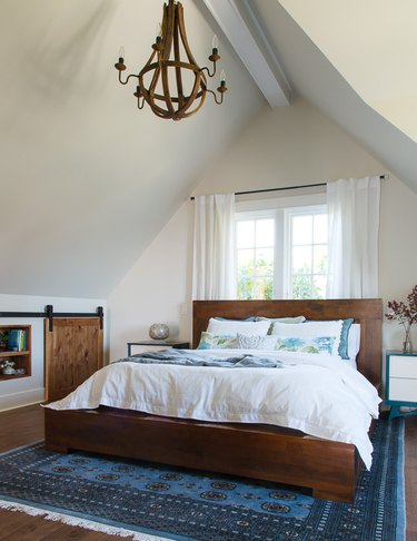 attic storage in bedroom with midcentury bed and sliding barn door