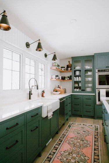 green kitchen cabinets with black hardware and area rug on floor