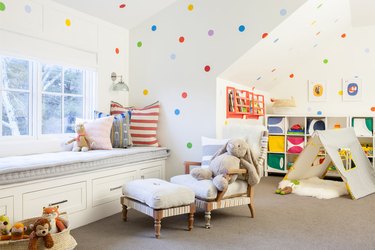 Attic playroom with polka dot walls, window seat, and tent