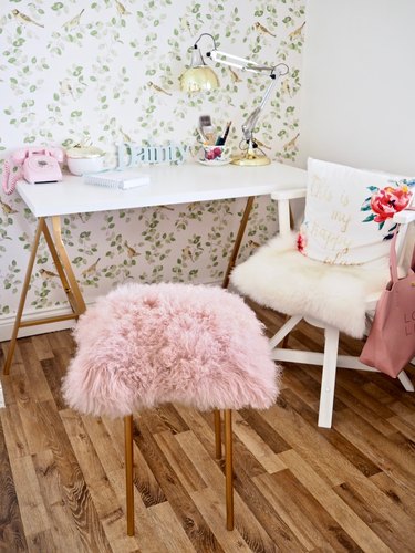 A pink furry stool in front of a desk.