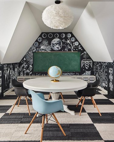 attic game room with black and white checkered rub, chalkboard walls, green chalkboard, round white tale, mid century modern chairs, globe, coral pendant lamp.
