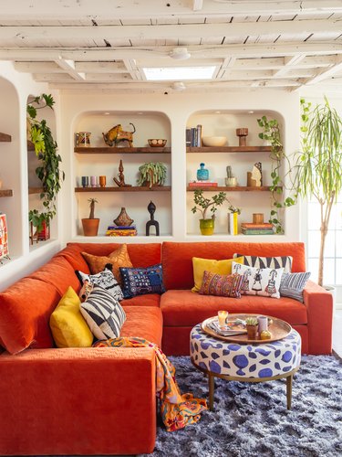 cream bohemian living room with orange sofa