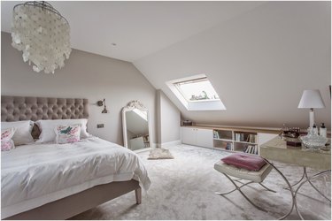 attic storage in bedroom with low storage unit and capiz shell chandelier