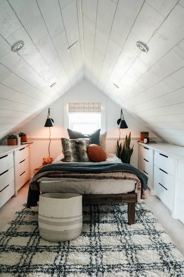 Attic bedroom idea with plaid area rug and storage dressers
