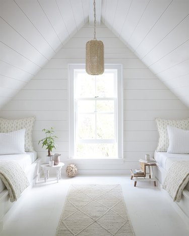 Attic bedroom idea with white shiplap walls and ceiling and twin beds