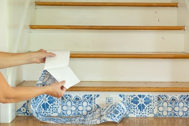 Adhere removable wallpaper to stair riser