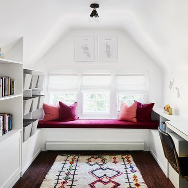 small attic library with pink window seat and pillows