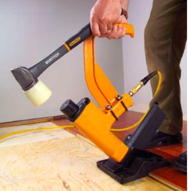 Man installing flooring with a nailer.