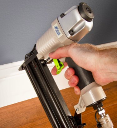 Installing baseboards with a nailer.