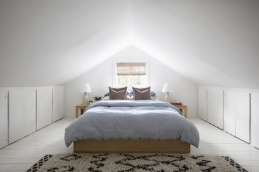 Small attic ideas for white painted walls and a minimalist oak-framed bed.