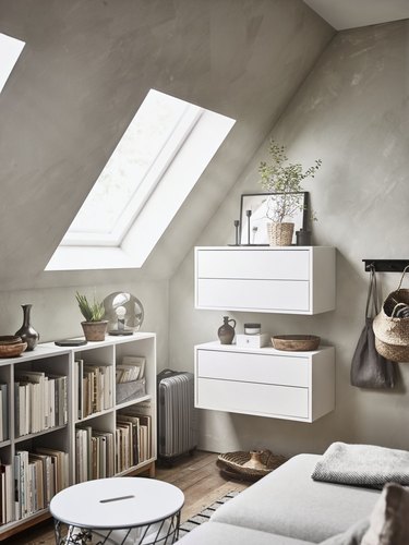 small attic library with gray walls and white bookcases and storage