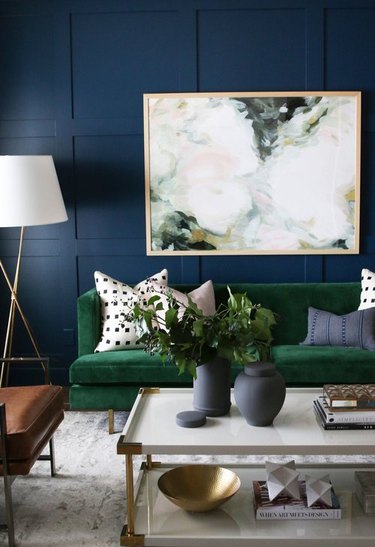 navy blue living room idea with velvet green sofa filled with accent pillows