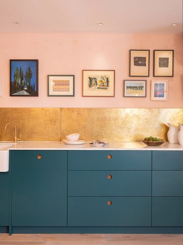 gold metallic kitchen backsplash with blue cabinets and pink walls