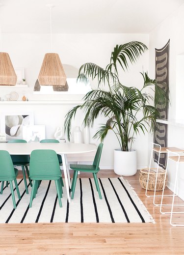 white bohemian dining room with green chairs and woven pendant lights