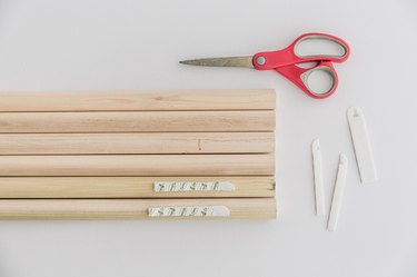 Stick sandwiched pairs of picture hanging strips to the top and bottom edges of the dowels.