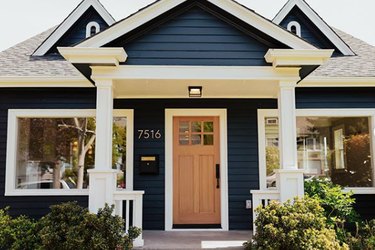 craftsman bungalow with blue home exterior in navy with white accents and natural door