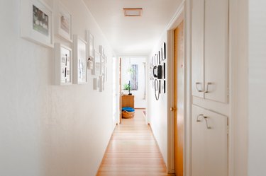 Wood floor hallway with built-in white cabinets, and framed wall photos.